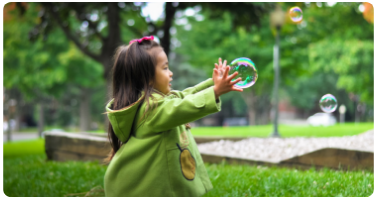 Young toddler trying to capture a soap bubble