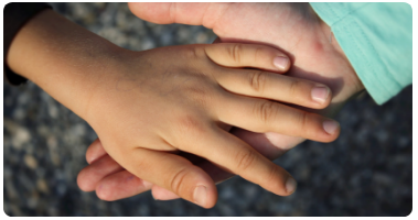 Hand of an adult and child clasping