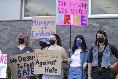 A group of protesters wearing masks hold signs that say, “Misogyny is an Epidemic”, “This is why we still need Pride”, and “We deserve to feel Safe”. Abigail Mitchell stands in the centre holding a sign that says “UG and UW Against Hate.”
